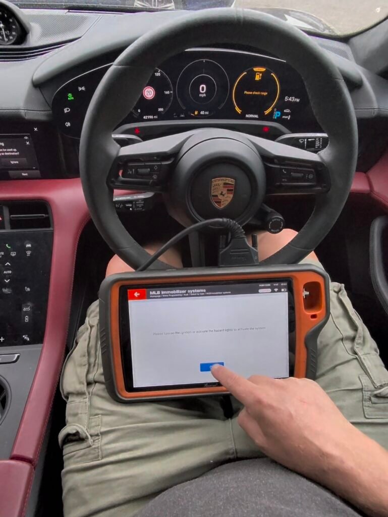 Key programming tool connected to a 2023 Porsche Taycan at the steering wheel